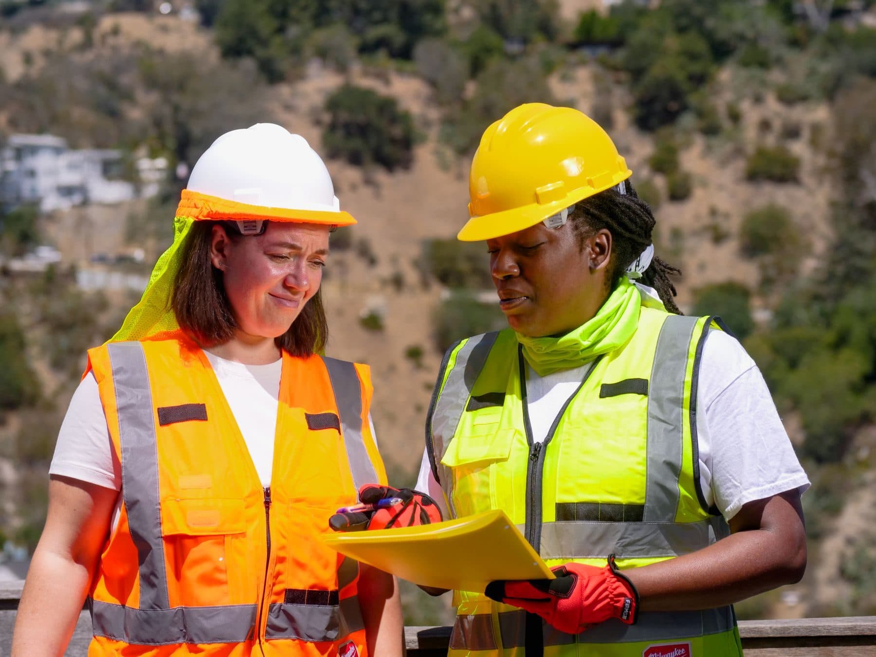 Two occupational health and safety colleagues reviewing notes on site