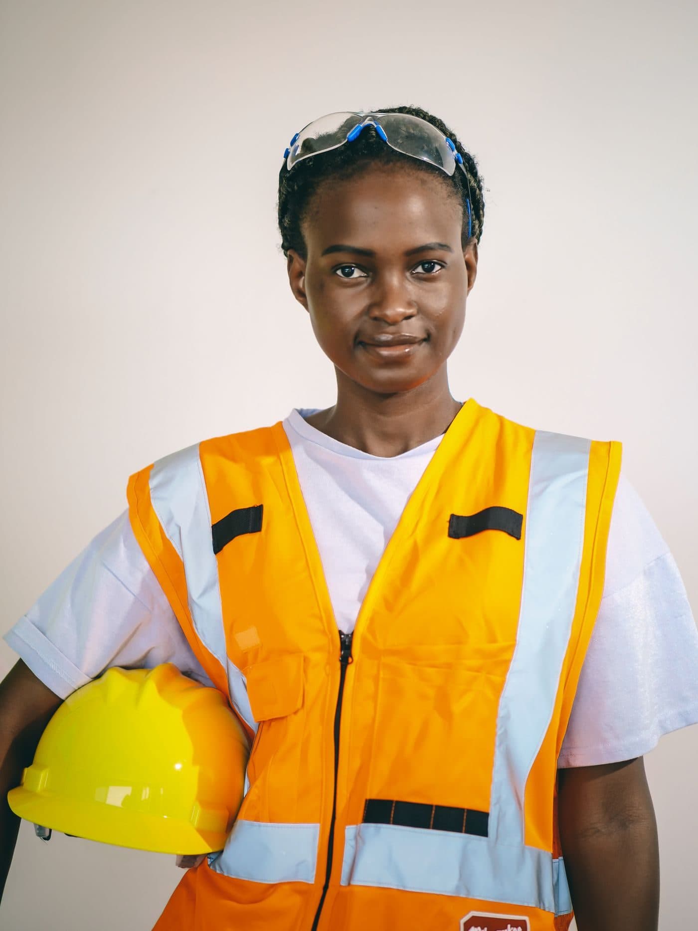 An occupational health and safety officer in a high-visibility vest holding a hard hat
